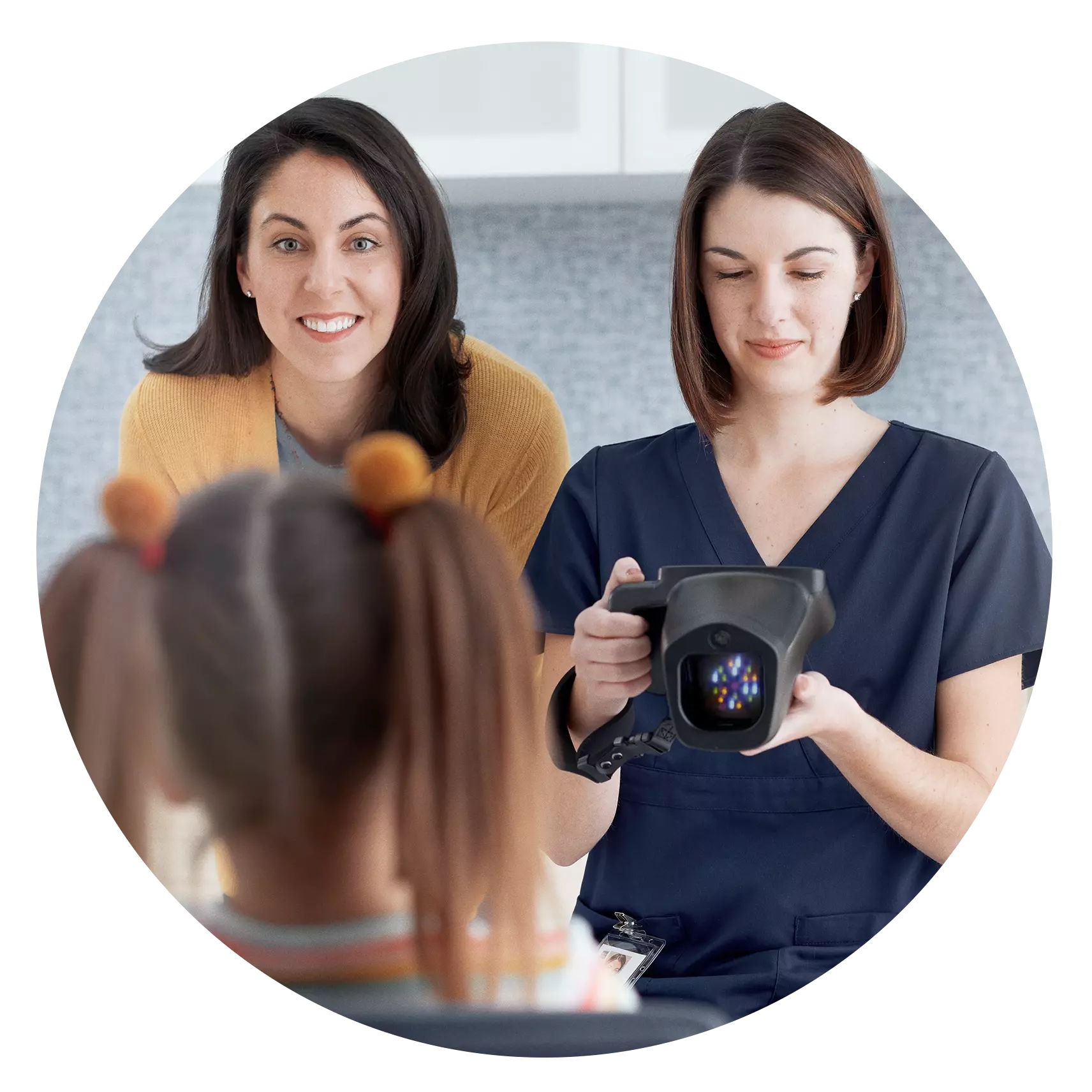 A healthcare professional next to a smiling parent points the spot vision screener at a child